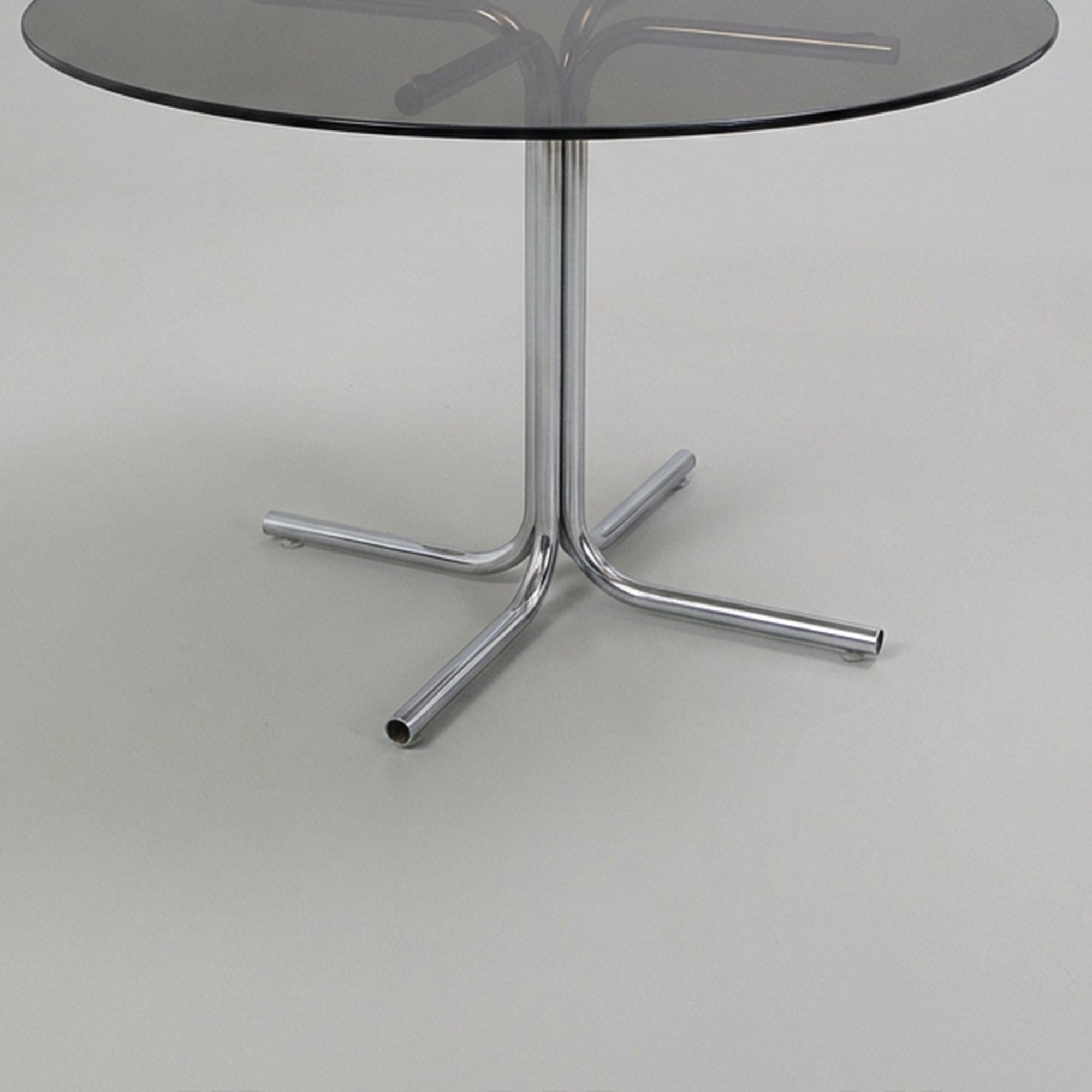 Dining table with tubular base and smoked glass top