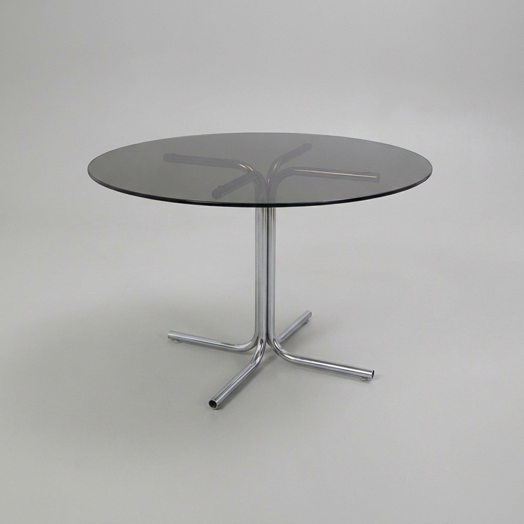 Dining table with tubular base and smoked glass top